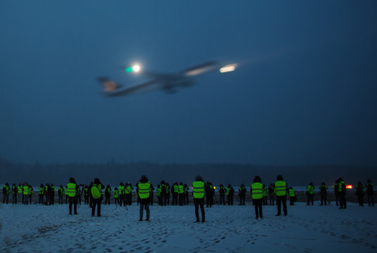 A Big Group Of Photographers In Reflective Jackets Watching And Shooting A Plane Take Off