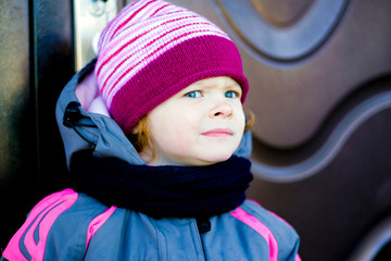 redhead beautiful little girl warmly dressed and wrapped in a scarf playing outside,close up