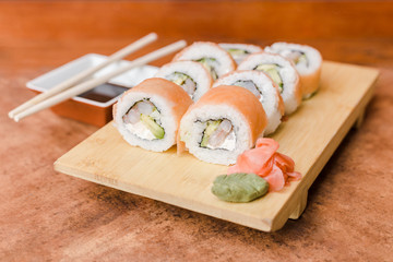 Sake roll with ginger, wasabi and soy sauce on a wooden table