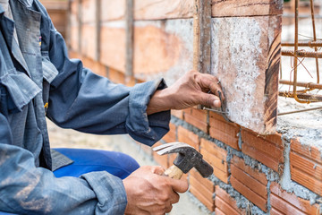 Hand of worker holding hammer in construction work. Worker using hammer  for hitting the nail.