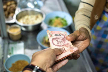 Obraz na płótnie Canvas Hand receiving money in Thai currency one-hundred Baht.