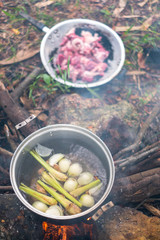 Ingredient of soup in boil water in a pot on campfire.