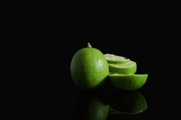 Fototapeta na wymiar Green Lime with sliced on black background