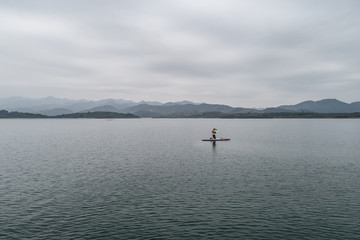 aerial view of a man taking photo with cellphone on the Stand-Up-Paddleboard
