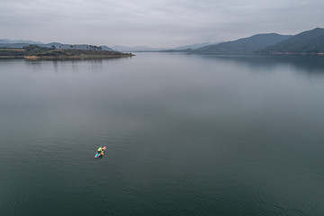 aerial view of a man stand up paddle boarding on the lake	