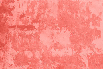Stone wall with cracked, peeling plaster and paint as texture, background, coral toned