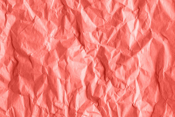 Fototapeta premium Texture of crumpled rough wrapping paper in coral toned, abstract background