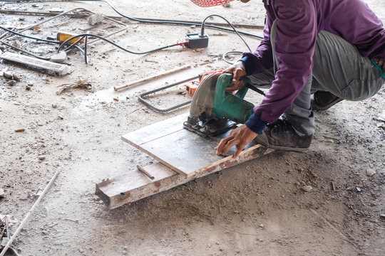Worker is using wood circular  cutter saw cutting wooden board.