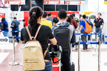 Young Thai woman  standing in queue waiting to check-in registration before flight. Back view.