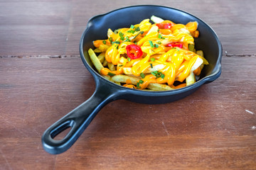 French fries with cheese in black pan.