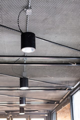Turned-on warm tone light bulbs in black lamps lined up on ceiling - rustic and loft style.