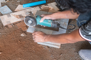 Worker cutting a tile using an angle grinder in home improvement and renovation.