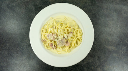 Spaghetti Carbonara in a dish White on a stone floor table.