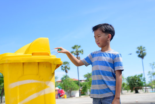 Young Boy Hand Trow Plastic Bottle In A Yellow Bin