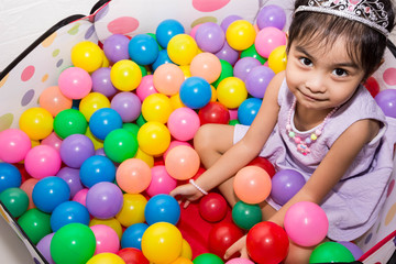 Fototapeta na wymiar Female asian child girl while sitting and playing with colorful plastic balls