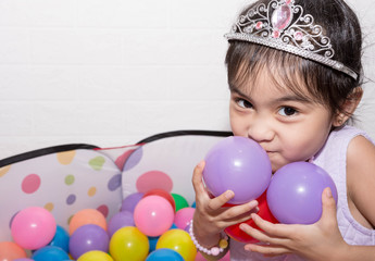 Female asian child girl  while sitting and playing with colorful plastic balls