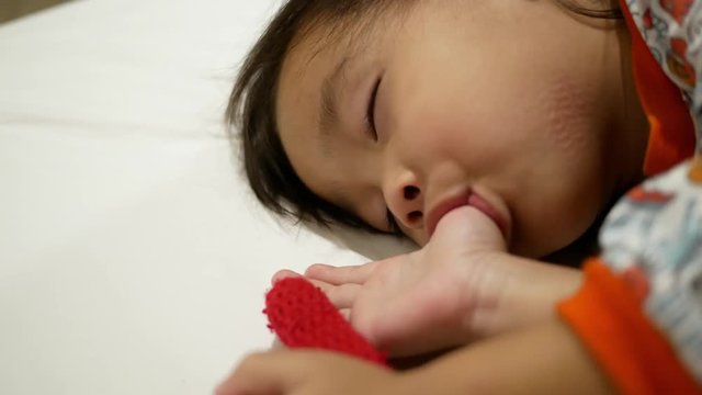 Asian little child are thumb sucking as sleeping in the bedroom. Health care concept.