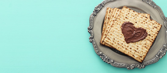 Pesah celebration concept (jewish Passover holiday) with chocolate heart over matzah. Top view flat lay