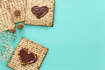 Pesah celebration concept (jewish Passover holiday) with chocolate heart and colorful candies over matzah. Top view flat lay