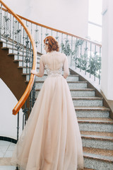 Fototapeta premium The bride is in an expensive hotel on the stairs. Wedding photo shoot in a beautiful dress.