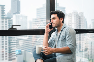 Technology Smartphone and Communication Concept, Portrait of Business Man is Calling on Cellphone at Office Workplace. Businessman is Communicating Call on Mobile phone While Drinking Coffee.