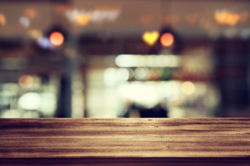 Image of wooden table in front of abstract blurred restaurant lights background