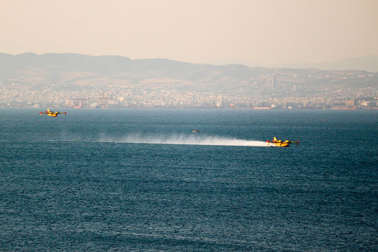 Seaplane lands on water in mediterranean sea with city of Thessaloniki on the background, Greece