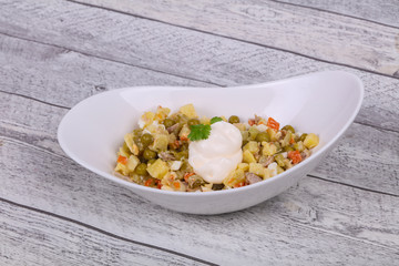 Traditional Russian salad with chicken in the white bowl