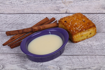Condenced milk in the bowl with sinnamon and pastry