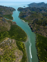 Obraz premium Aerial view of bay and river in Park Kilim Geoforest, Langkawi, Malaysia. Beautiful mountains, sea and trees around the river. Boat sailing on the river