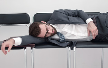 tired businessman sleeping on chairs in the office hallway