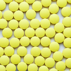 Small yellow pills on a white background close-up.