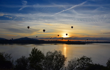 Hot air balloons flying in the air above Lake Burley Griffin, as part of the Balloon Spectacular Festival in Canberra.