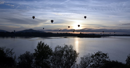 Hot air balloons flying in the air above Lake Burley Griffin, as part of the Balloon Spectacular Festival in Canberra.