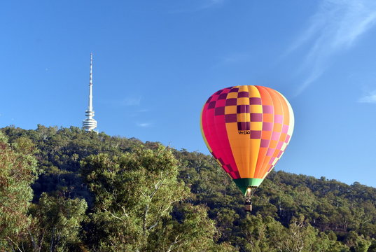 Canberra, Australia - March 10, 2019. Hot air balloon flying in the air above Black Mountain and Telstra Tower, as part of the Balloon Spectacular Festival in Canberra.