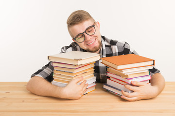 People, knowledge and education concept - smiling man sitting at the wooden table with books