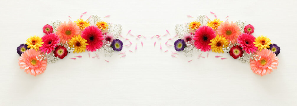 spring bouquet of pink, yellow, orange and purple flowers over white wooden background. top view, flat lay