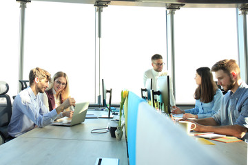 Young modern colleagues in smart casual wear working together while spending time in the creative office.