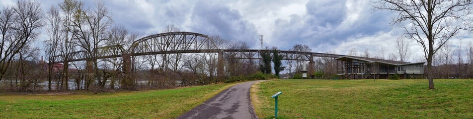 Fototapeta premium Train track railway bridge views along the Shelby Bottoms Greenway and Natural Area over Cumberland River frontage trails, Music City Nashville, Tennessee. United States.