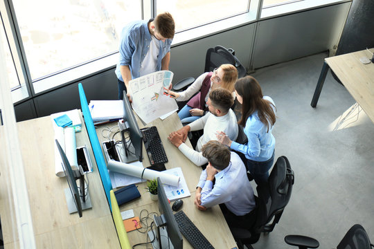 Top view of young modern colleagues in smart casual wear working together while spending time in the office.