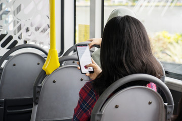 Woman sitting with a phone inside the bus