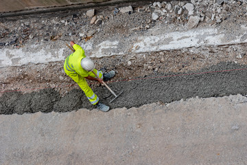 obrero esparciendo cemento sobre una zanja o obrero pavimentando o echando cemento para colocar una acera