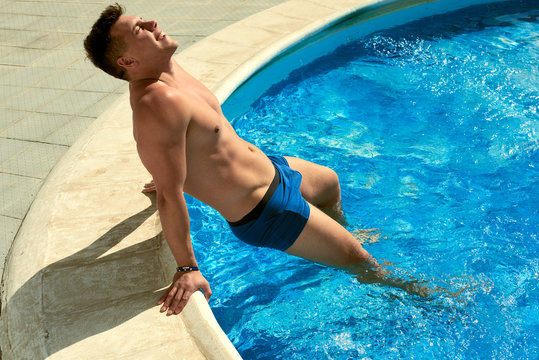 a man by the pool is swimming and sunbathing