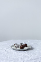 Obraz na płótnie Canvas Homemade vegan chocolate candies with grated coconut, nuts, cocoa on a white background with copy space