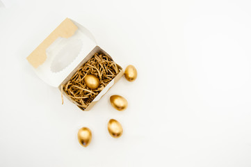 Golden Easter Eggs in a box with golden stars on white background . Easter Holiday concept abstract background copyspace top view