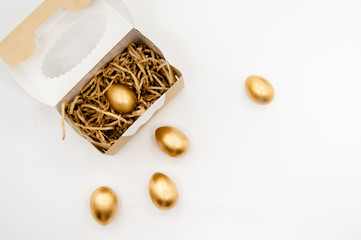 Golden Easter Eggs in a box with golden stars on white background . Easter Holiday concept abstract background copyspace top view