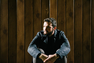 Obraz premium A man with a beard in a jacket and sweater posing on the street at night. Advertising of men's clothing