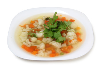 Porcelain plate with vegetable soup on white background