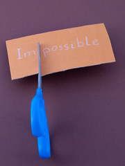 scritta impossible  impossibile con forbice che taglia le lettere IM