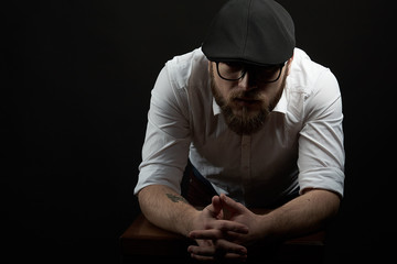 young handsome man in the glasses of struggle and mustache in a black cap and a white shirt...